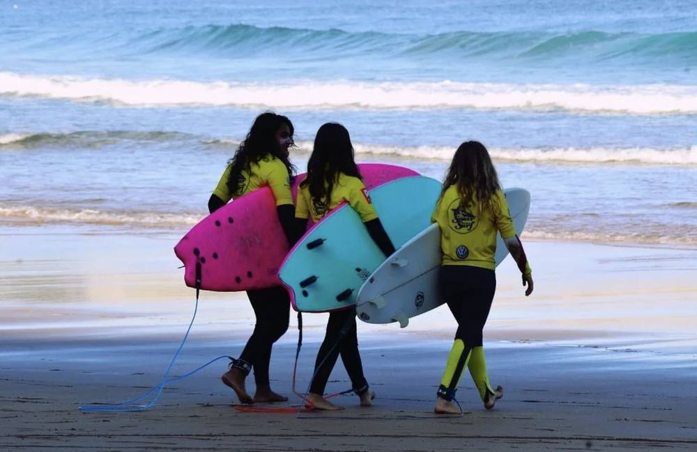 Alumnos con tablas de surf en la playa